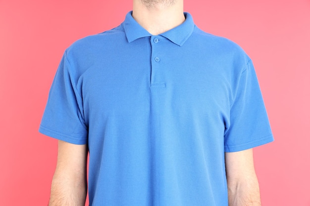 Hombre en polo azul en blanco sobre fondo rosa