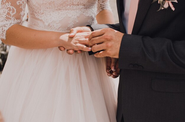 El hombre pone un anillo de bodas en la mano de una mujer.