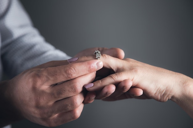 El hombre pone un anillo en el dedo de la mujer.