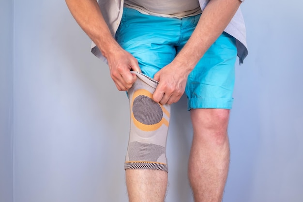 El hombre pone un aparato ortopédico estabilizador especial en la articulación de la rodilla lesionada