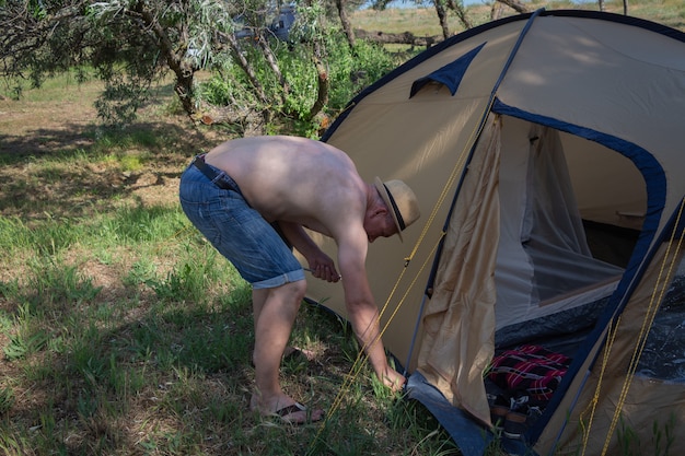 Un hombre pone una carpa en el campamento de recreación al aire libre de verano