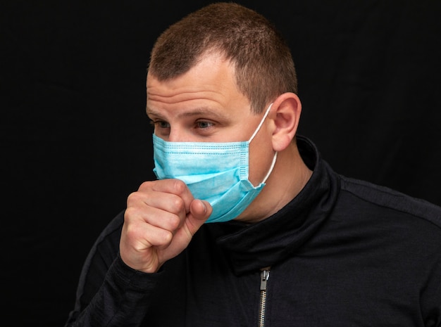 Un hombre se pone una máscara médica en la cara, instrucciones sobre cómo usar una máscara