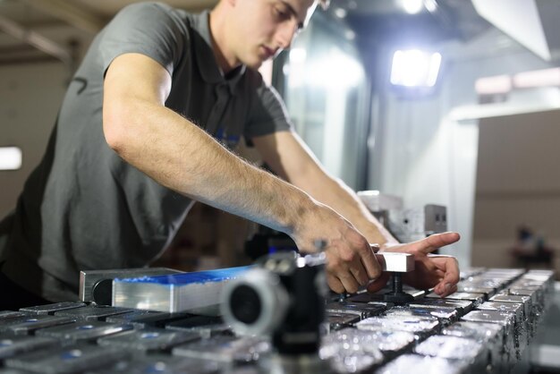 un hombre pone una pieza de aluminio en una máquina cnc y prepara una máquina de procesamiento.