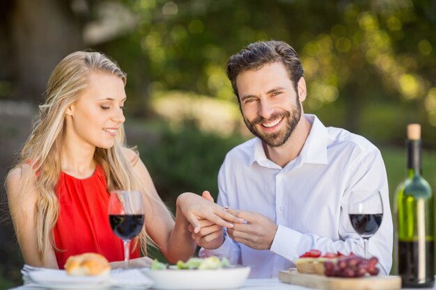 Hombre poniendo un anillo en el dedo de la mujer en el restaurante