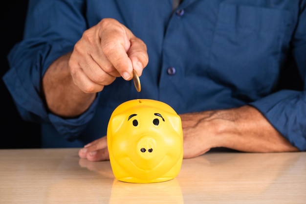 Un hombre poniendo monedas en una alcancía para ahorrar concepto de dinero.