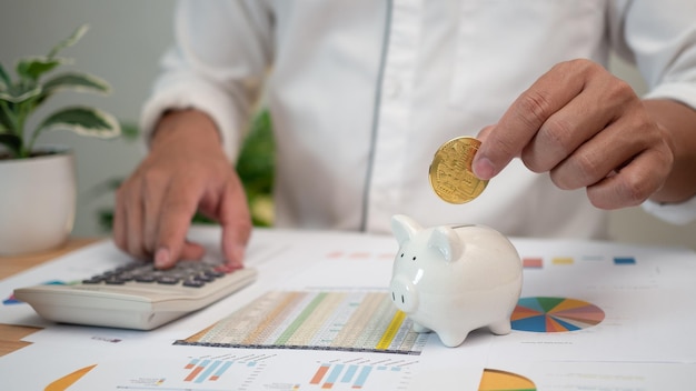 Hombre poniendo monedas en la alcancía y usando la calculadora de impuestos sobre la renta personal para pagar impuestos