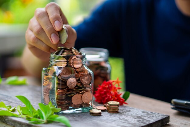 Hombre poniendo monedas en una botella de vidrio por dinero