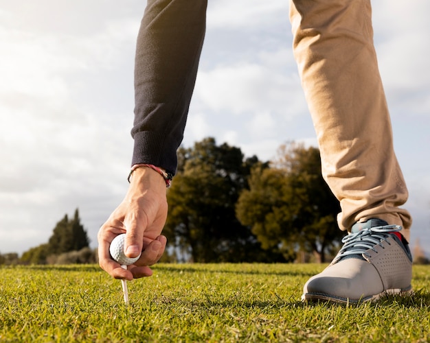 Foto hombre poniendo una pelota de golf en el tee