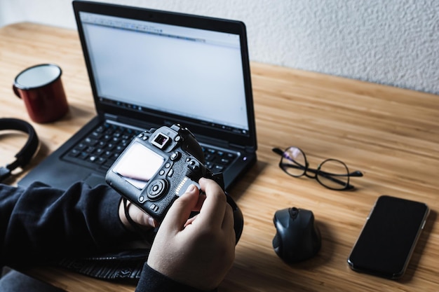 Foto el hombre está poniendo una tarjeta de memoria en su cámara con la computadora portátil en segundo plano.