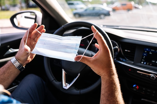 Hombre poniéndose máscara protectora en el coche