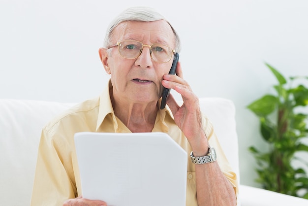 Hombre de popa anciano leyendo documentos en el teléfono