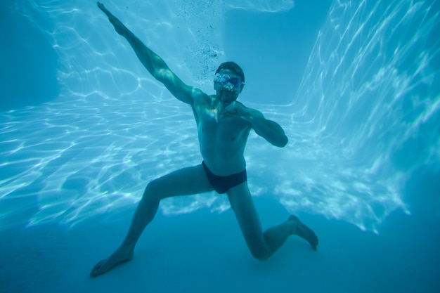 Hombre posando bajo el agua en la piscina