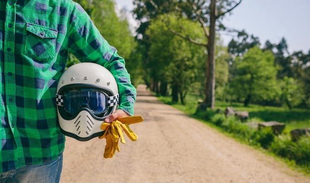 Hombre posando con casco de moto y guantes