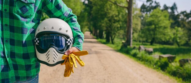 Hombre posando con casco de moto y guantes