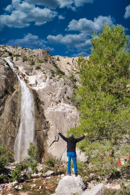 hombre posando en el río con cascada