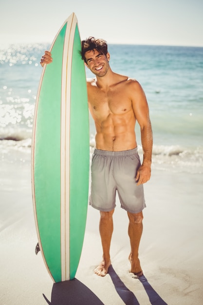 Hombre posando con tabla de surf