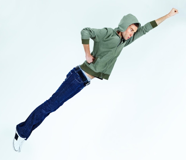 Hombre en pose de superhéroe volador con ropa casual de moda y ropa de calle elegante aislada en fondo blanco Energía despreocupada con modelo masculino joven está volando y posando en jeans y sudadera con capucha