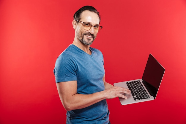 Foto hombre positivo emocional feliz usando la computadora portátil.