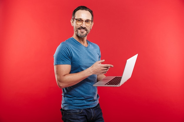 Hombre positivo emocional feliz usando la computadora portátil.