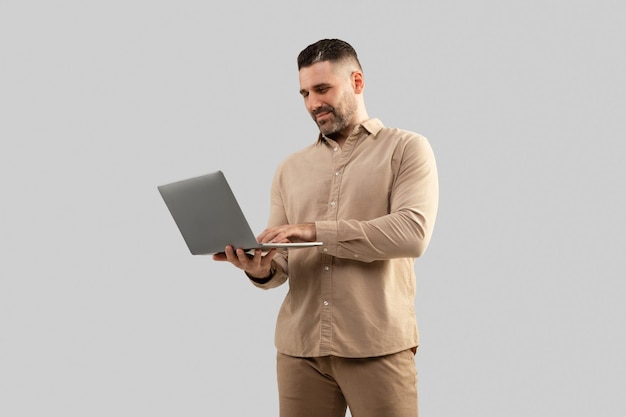 Hombre positivo de mediana edad escribiendo en una computadora portátil navegando en Internet trabajando en línea de pie en