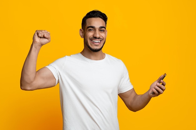 Hombre positivo del Medio Oriente que comercia en línea disfrutando del éxito