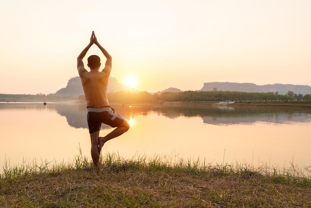 Un hombre practica yoga en el lago de la montaña.