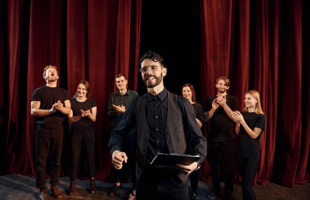 Foto el hombre está practicando su papel grupo de actores con ropa de color oscuro en el ensayo en el teatro