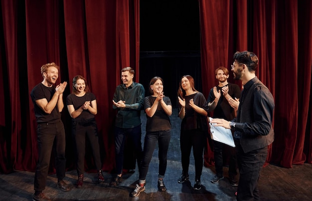 Foto el hombre está practicando su papel grupo de actores con ropa de color oscuro en el ensayo en el teatro