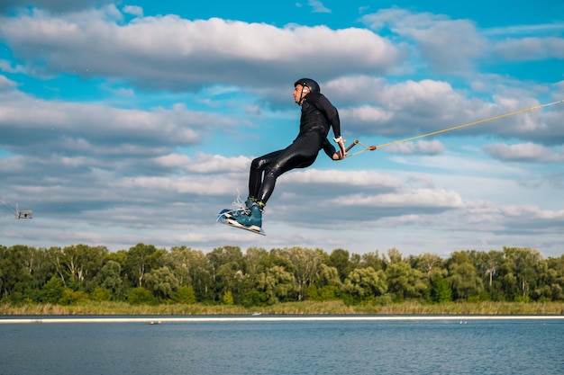 Hombre practicando la técnica de saltar sobre el agua con rotación durante el entrenamiento de wakeboard