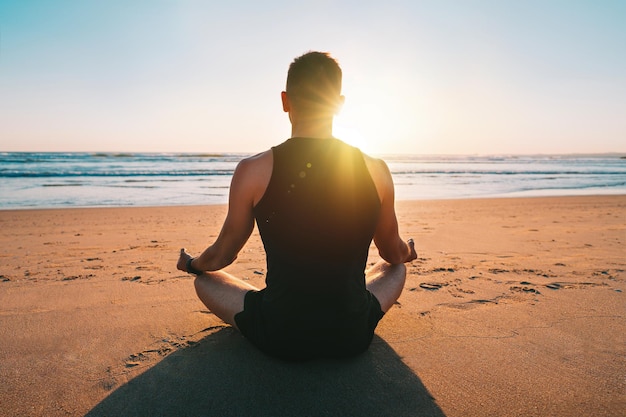 Hombre practicando yoga y medita en la playa al atardecer Relajación y armonía