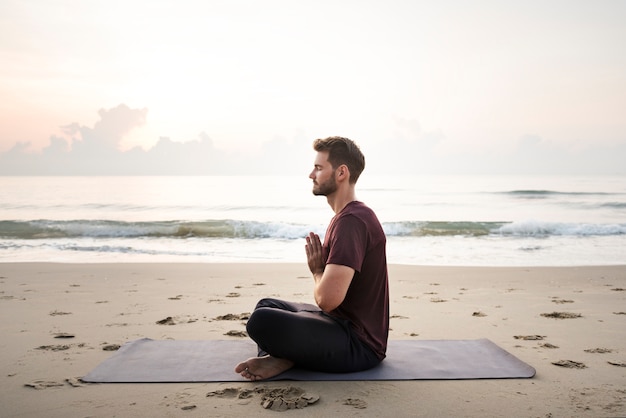 Hombre practicando yoga en la playa