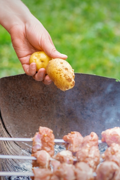 Hombre prepara carne de barbacoa con papas