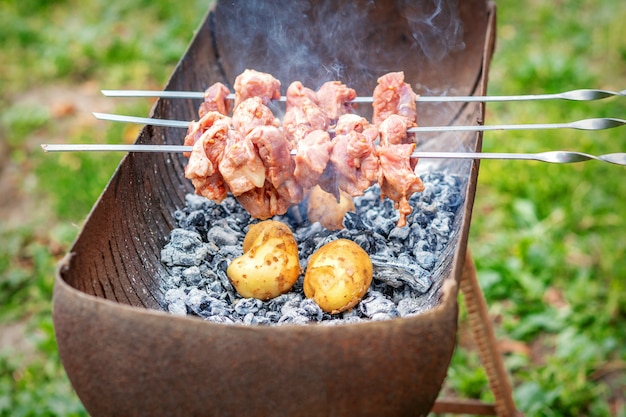 Hombre prepara carne de barbacoa con papas