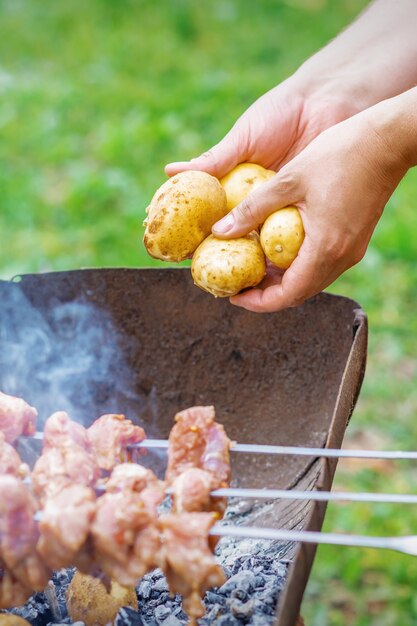 Hombre prepara carne de barbacoa con papas