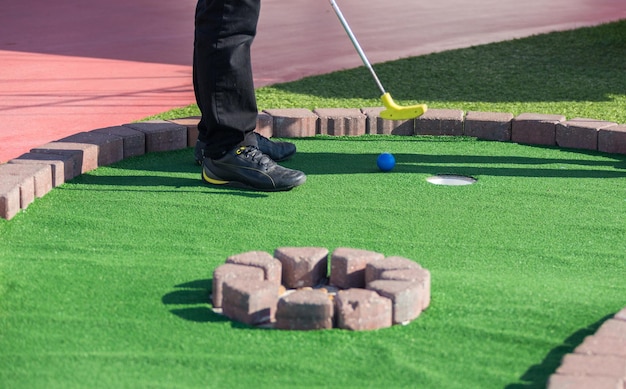 Un hombre se prepara para golpear una pelota durante un juego de mini golf