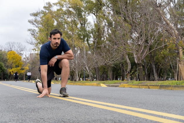 El hombre se prepara para trotar en el parque, vista al ras