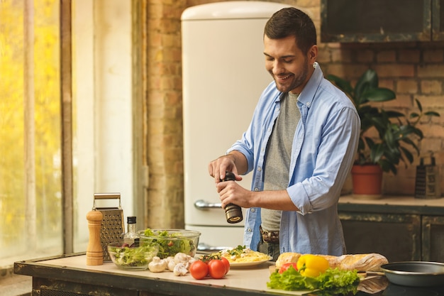 Foto hombre preparando comida deliciosa y saludable en la cocina de casa en un día soleado