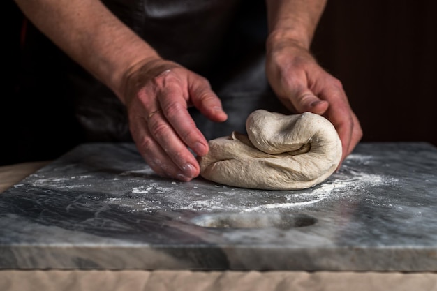 Hombre preparando masa para pizza en mesa de mármol