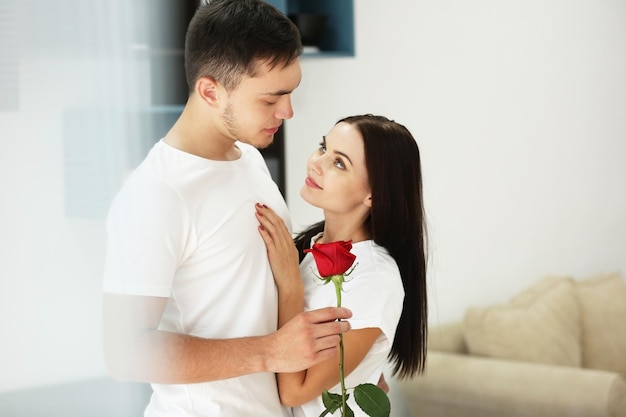 Hombre presentando rosa roja a novia en casa