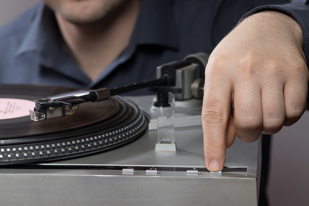 Un hombre presiona un botón de tocadiscos de vinilo gramófono.