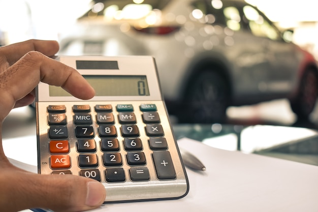 Foto hombre presionando la calculadora para las finanzas del negocio en el salón de muestras del coche