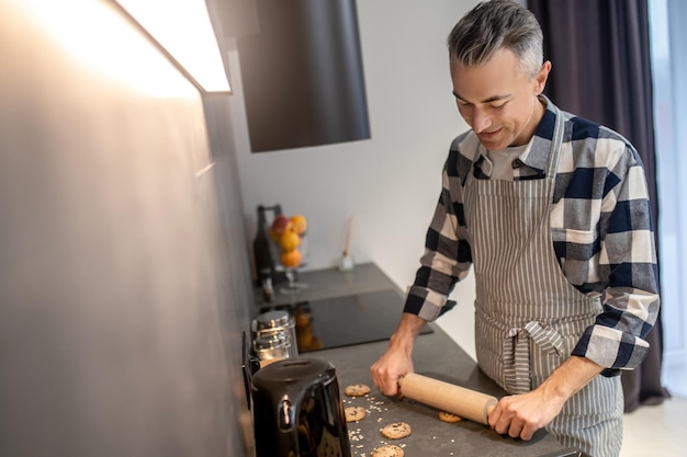 Hombre presionando el rodillo en la superficie de la galleta