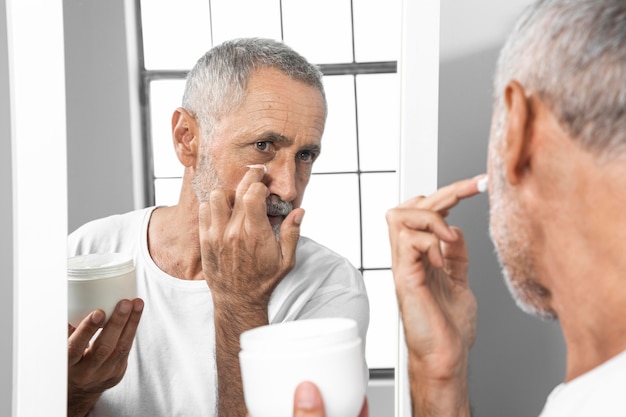 Foto hombre de primer plano aplicar crema facial