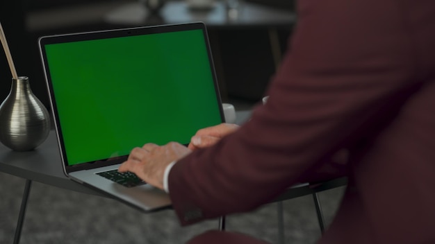 Hombre de primer plano armado enviando mensajes de texto a una computadora portátil de pantalla verde en el director del gabinete usando una computadora