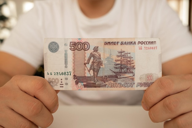 Foto un hombre de primer plano sostiene en sus manos un billete desplegado con un valor nominal de 500 rublos dinero ruso