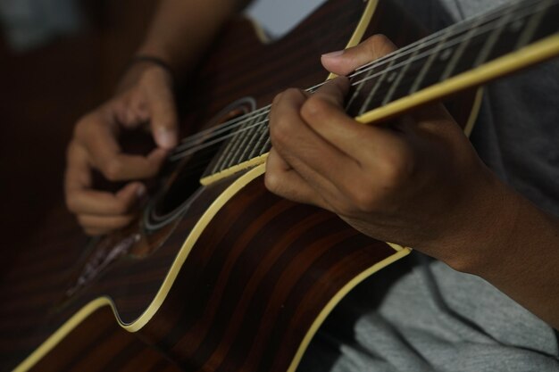 Foto hombre de primer plano tocando la guitarra acústica