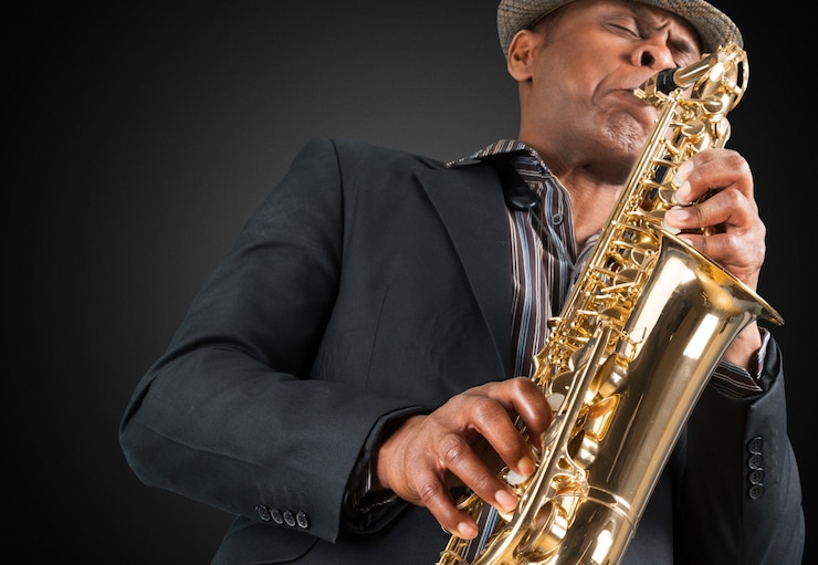 Foto hombre de primer plano tocando el saxofón en el fondo