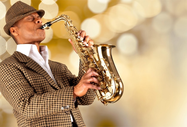 Foto hombre de primer plano tocando el saxofón sobre fondo borroso