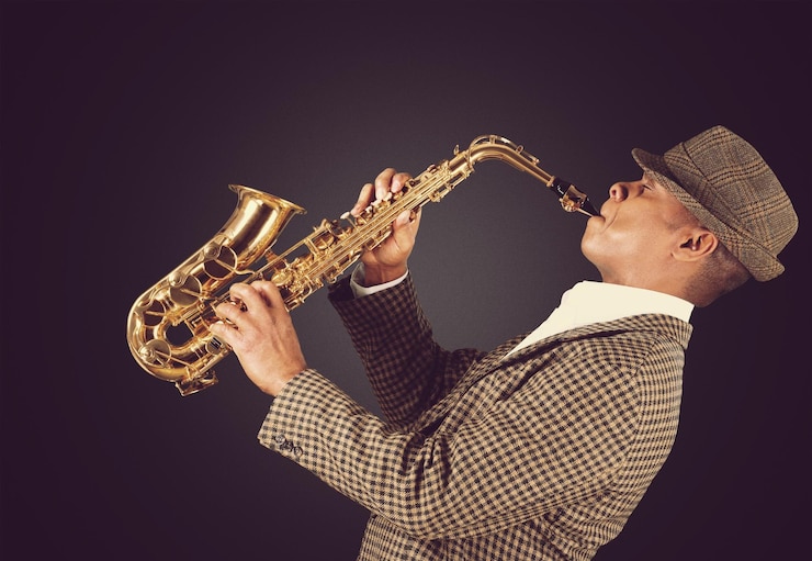 Foto hombre de primer plano tocando el saxofón sobre fondo oscuro