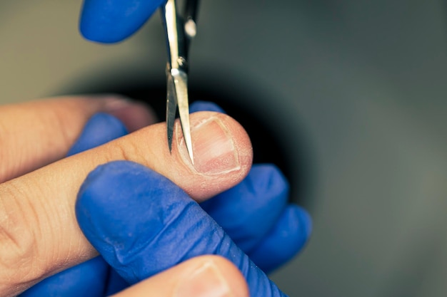 El hombre en los procedimientos en el salón de manicura Spa manicura eliminación de cutículas tijeras hermosas manos masculinas